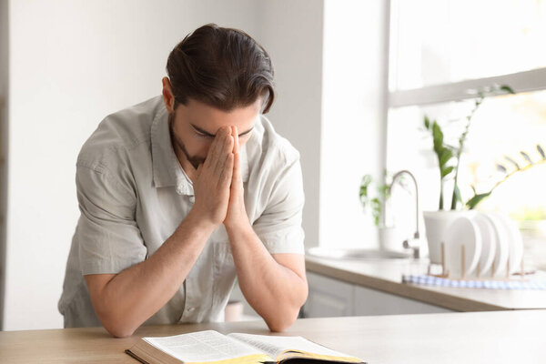 Religious man with Bible praying at  home