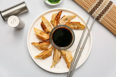 Kızarmış Japon gyoza tabağı ve gri arka planda soya sosu.