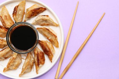 Kızarmış Japon gyoza tabağı ve leylak arkaplanda soya sosu.
