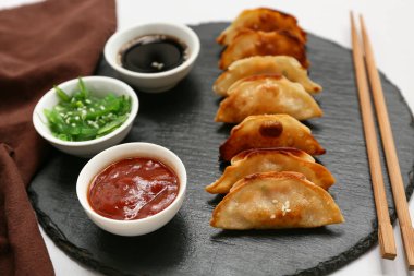 Gri arka planda deniz yosunu salatası ve soslu kızarmış Japon gyozası.