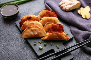 Kızarmış Japon gyozası ve koyu arkaplanda bir kase soya sosu olan kara tahta.