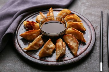 Kızarmış Japon gyoza tabağı ve siyah arka planda soya sosu.