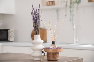Reed yayıcı, lavanta çiçekli vazo ve mutfak masasında gerekli yağ, yakın plan.