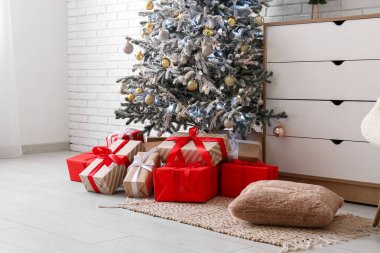 Noel ağacı hediyeler ve beyaz tuğla duvarın yanındaki çekmeceler.