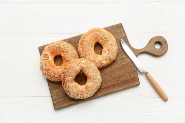 Beyaz ahşap arka planda susam tohumlu lezzetli simit kesme tahtası
