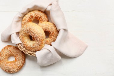 Beyaz ahşap arka planda susam tohumlu bir kase lezzetli simit.