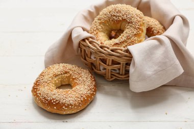 Beyaz ahşap arka planda susam tohumlu bir kase lezzetli simit.