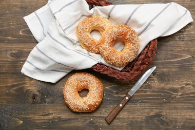 Tahta arka planda susam tohumlu bir sepet lezzetli simit.