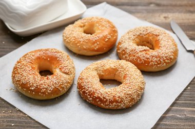 Ahşap arka planda susam tohumlu lezzetli simit kağıtları.