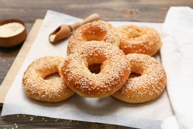 Ahşap arka planda susam tohumlu lezzetli simit kağıtları.