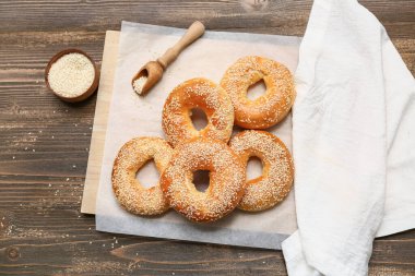 Ahşap arka planda susam tohumlu lezzetli simit kağıtları.