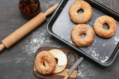 Tahta pano ve siyah zemin üzerinde susam tohumları olan lezzetli simit pişirme kabı.