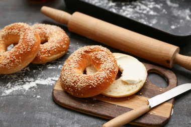 Tahta tahta tahta tahtada susam tohumlu lezzetli simit ve siyah arka planda taze tereyağı.