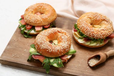 Beyaz arka planda malzemeleri olan lezzetli bagel sandviçlerden oluşan ahşap tahta bir tahta tabela.