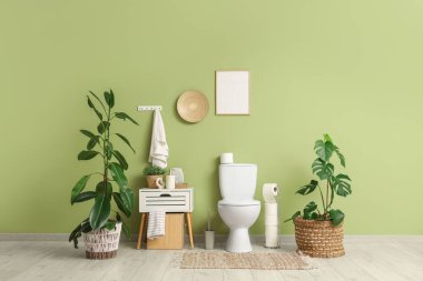 Tuvaletin içinde klozet, komodin ve bitkiler var.