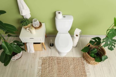 Seramik klozetli, komodinli ve çiçekli ışık tuvaleti.