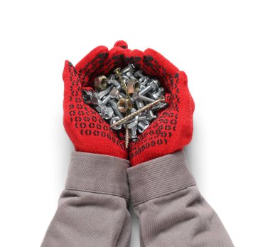 İşçinin elleri farklı musluk cıvataları, krom fındıklar ve beyaz arka planda vidalar tutuyor.