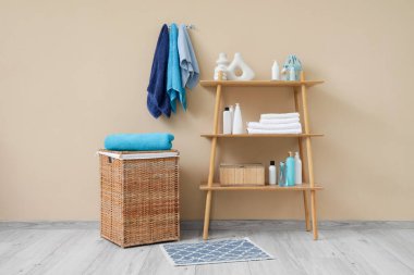 Mavi havlular, raf ünitesi ve sepeti olan banyonun içi.