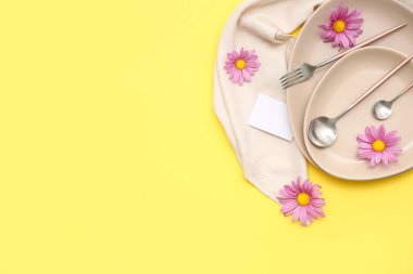 Sarı arka planda güzel kasımpatı çiçekleri olan şık bir masa.