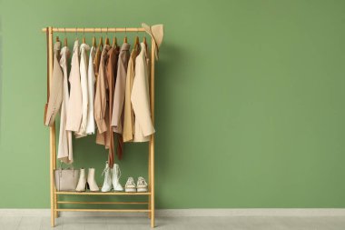 Yeşil duvarın yanında duran şık kıyafetlerle dizilin.