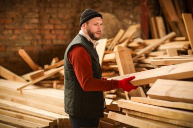 Erkek marangoz kereste fabrikasında tahta diziyor.