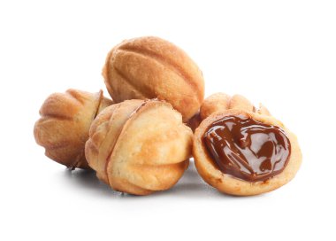 Beyaz arka planda kaynamış konsantre sütle pekçok tatlı ceviz şekilli kurabiye.