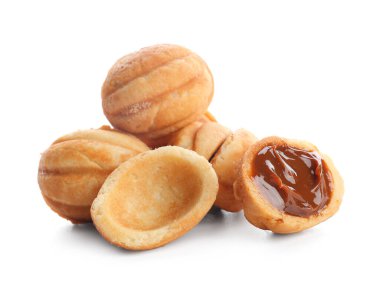 Beyaz arka planda kaynamış konsantre sütle pekçok tatlı ceviz şekilli kurabiye.