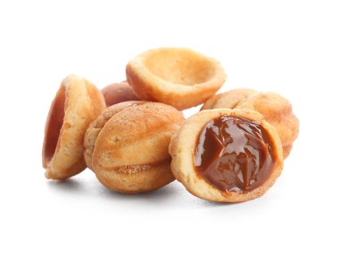 Beyaz arka planda kaynamış konsantre sütle pekçok tatlı ceviz şekilli kurabiye.