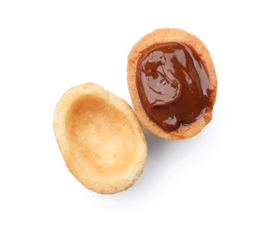 Beyaz arka planda kaynamış yoğunlaştırılmış sütle ceviz şekilli kurabiyeler.