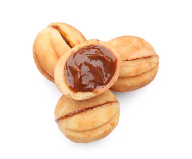 Beyaz arka planda kaynamış konsantre sütle pekçok tatlı ceviz şekilli kurabiye.