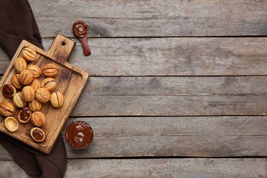 Ahşap zemin üzerinde kaynamış yoğunlaştırılmış sütle ceviz şeklinde kurabiyeler kesme tahtası.