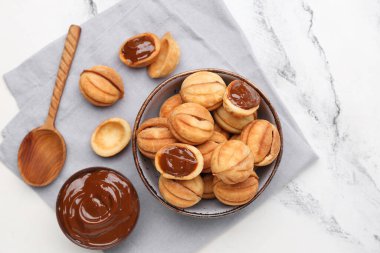 Beyaz arka planda kaynamış yoğunlaştırılmış sütle ceviz şeklinde kurabiyeler.