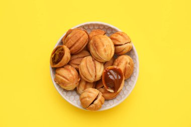 Sarı arka planda kaynamış konsantre sütle ceviz şeklinde kurabiyeler.