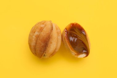 Sarı arka planda haşlanmış konsantre sütle ceviz şeklinde kurabiyeler.