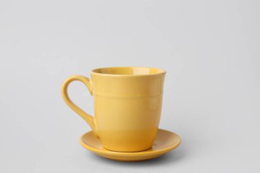 Sarı seramik bardak ve gri arkaplanda fincan tabağı