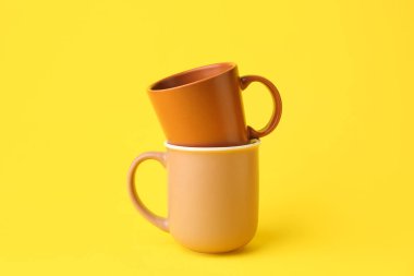 Sarı arkaplanda kahverengi seramik bardaklar