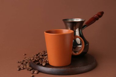 Kahverengi seramik fincanda kahve çekirdekleri ve renk arkaplanı.