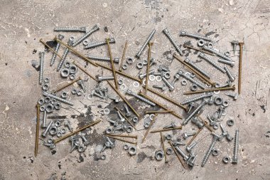 Gri grunge arka planında farklı vidalar ve krom fındıklar