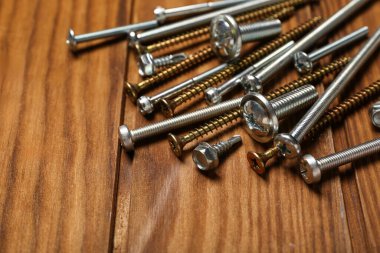 Kahverengi ahşap arka planda farklı sürgüler ve vidalar