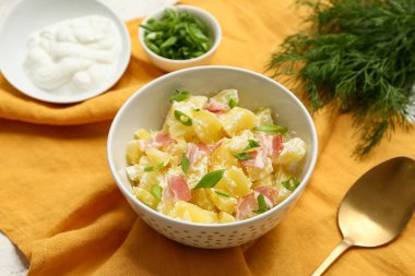 Pastırmalı, yeşillikli ve peçeteli bir tabak lezzetli patates salatası.