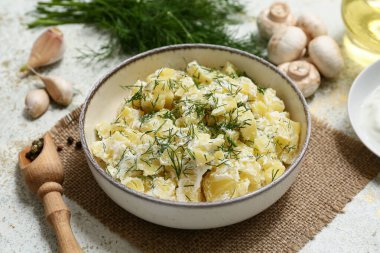 Bir kase lezzetli patates salatası, dereotlu, mantarlı, sarımsaklı ve biberli beyaz grunge soslu.
