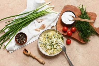 Bir kase lezzetli patates salatası, dereotu, yeşil soğan, domates ve bej renginde tuz.