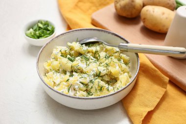 Beyaz arka planda dereotlu ve yeşil soğanlı patates salatası.