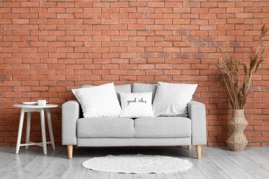 Gri kanepe, masa ve otların üzerinde yastıklar olan oturma odasının içinde.