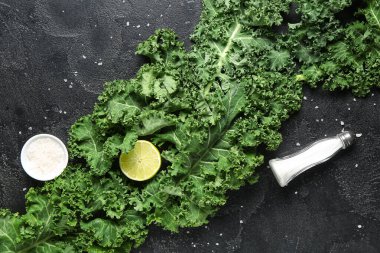 Limonlu taze lahana yaprakları ve siyah arka planda bir kase tuz.