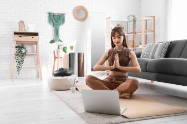 Evde meditasyon yapan genç ve güzel bir kadın.