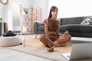 Evde meditasyon yapan genç ve güzel bir kadın.