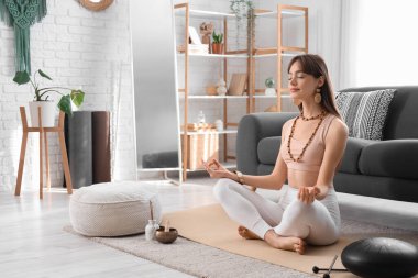 Evinde meditasyon yapan güzel genç bir kadın.
