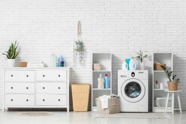 Çamaşır makinesi, çekmece ve deterjan dolu bir iç çamaşır odası.