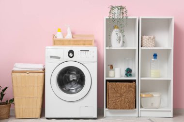 Çamaşır makinesi, sepet ve raf üniteleri olan modern çamaşır odasının içi.